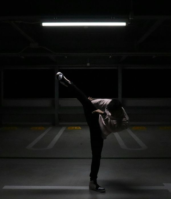Man performing a controlled strength exercise in a dark room.